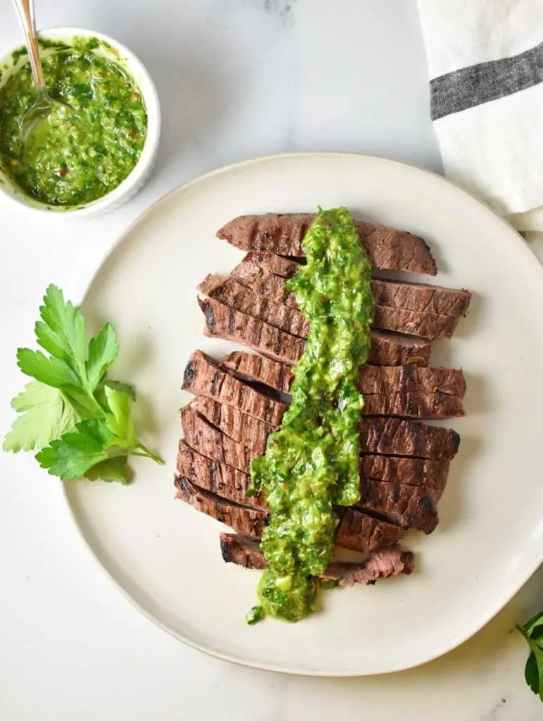 A steak on a plate with chimichurri sauce