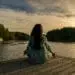 woman meditating on dock with migraine & anxiety