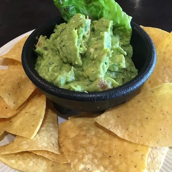 A small bowl of guacamole surrounded by chips