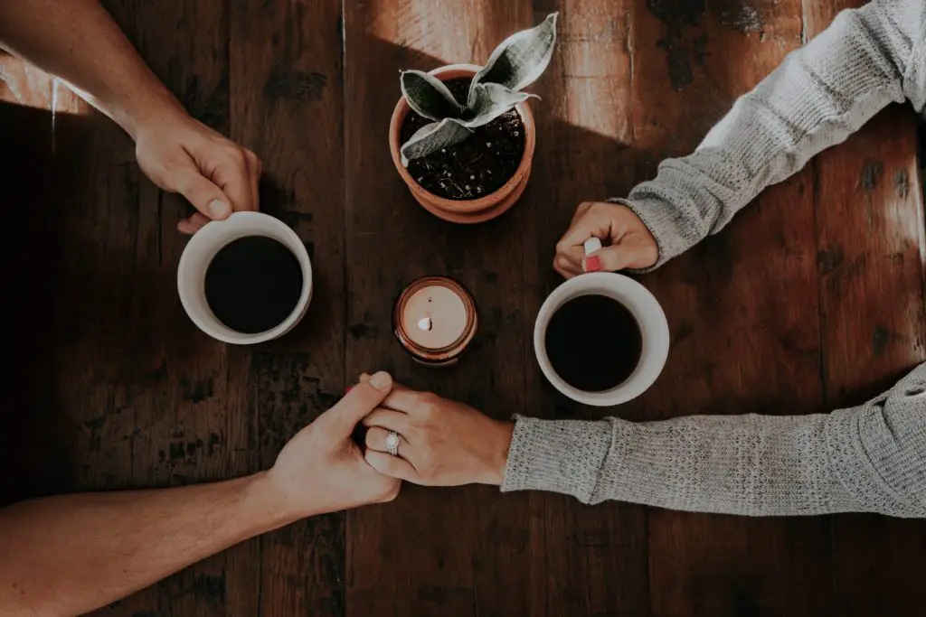 two people holding hands with coffee