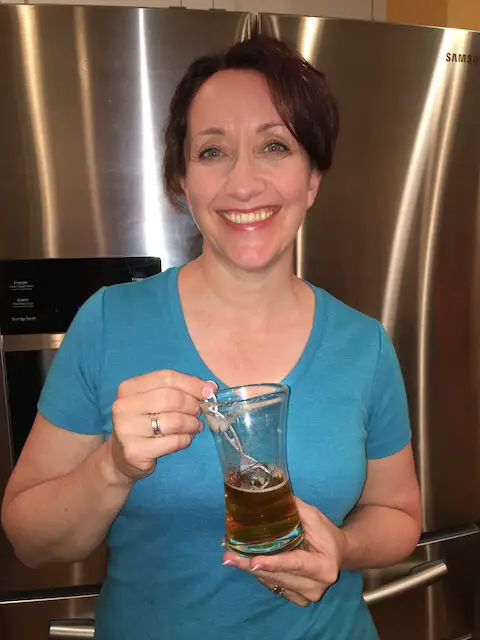 woman in blue shirt with glass of beer using PureWine The Wand to prevent migraine