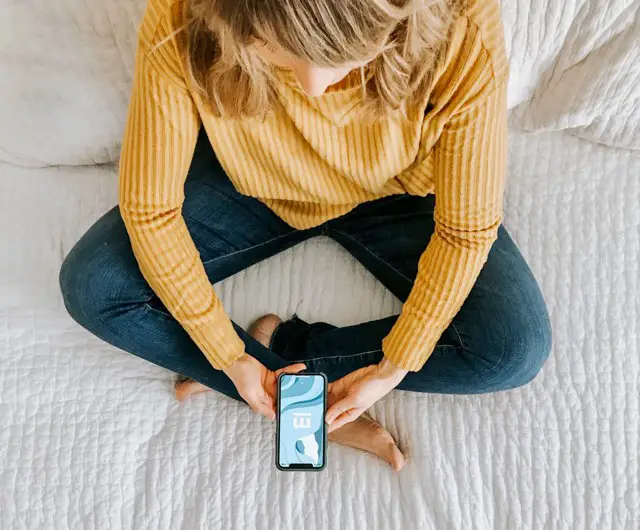 blond woman sitting cross legged using Migraine Healthline App