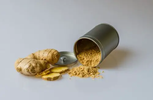 ginger root and a silver container on its side spilling ginger powder showing a natural migraine treatment