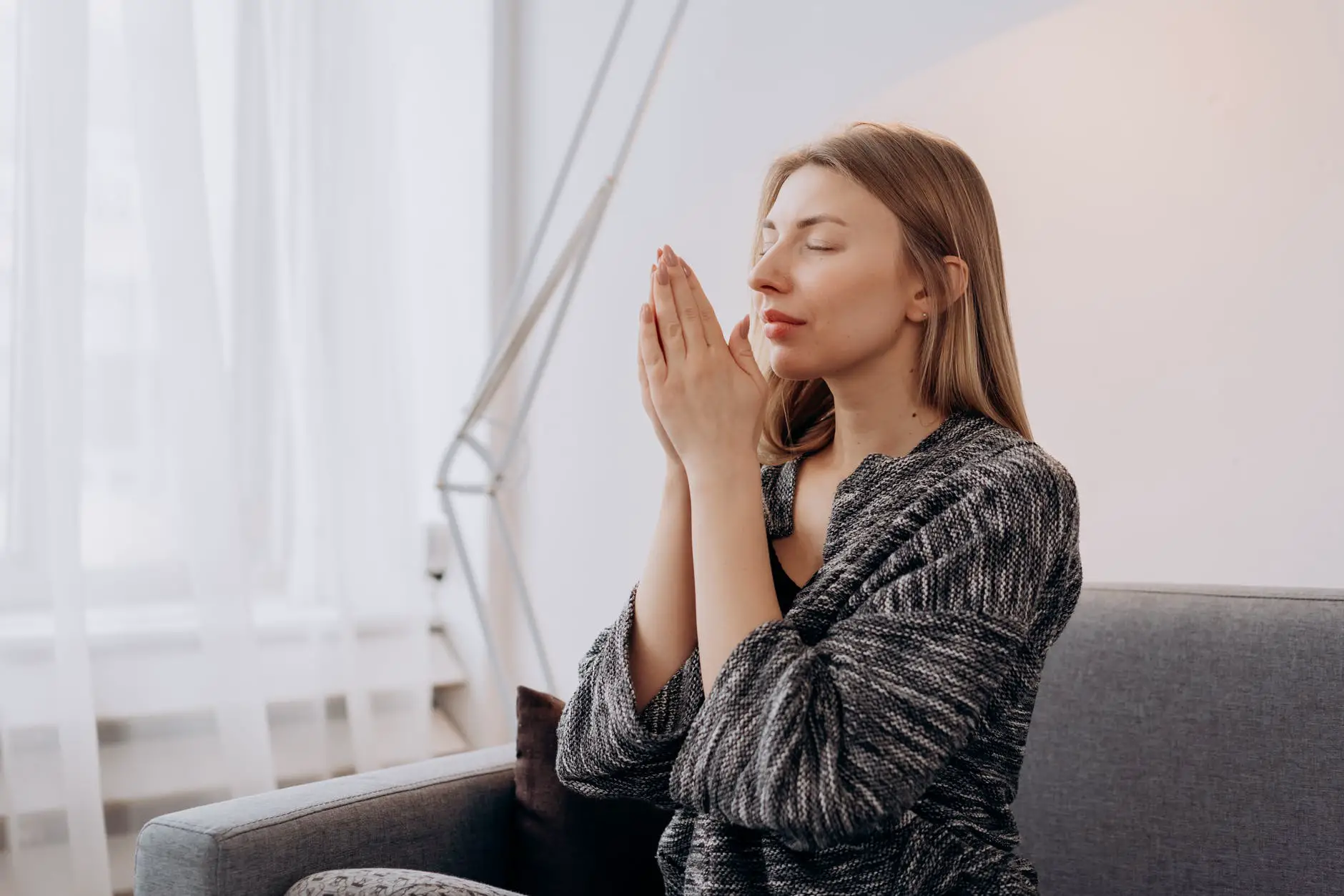 woman with her hands together rubbing essential oils between her palms and breathing deeply