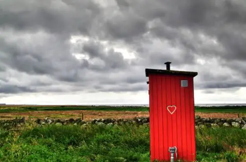 Picture of an red outhouse in a field for article on headache and constipation for