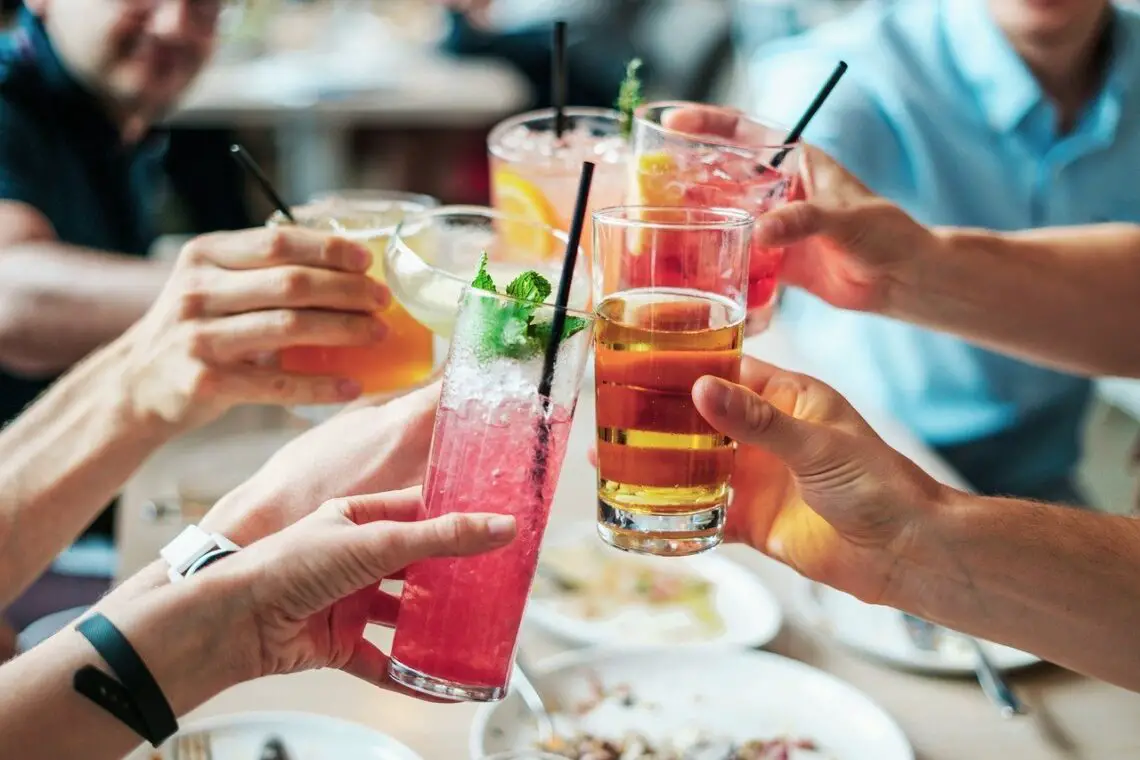 several hands holding drinks with the best and worst alcohols for migraine